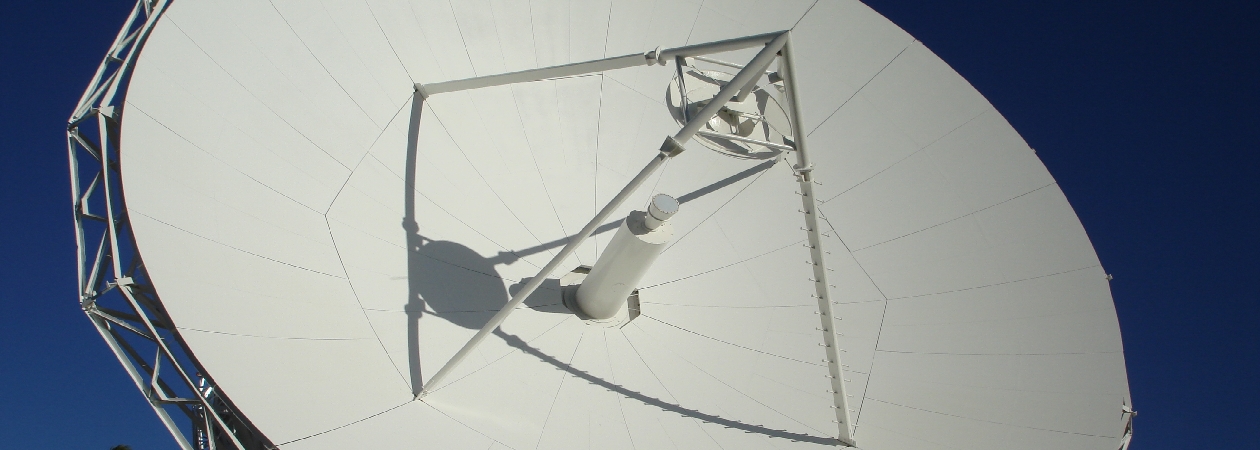 Large earth station antenna reflector and feed support against a blue sky