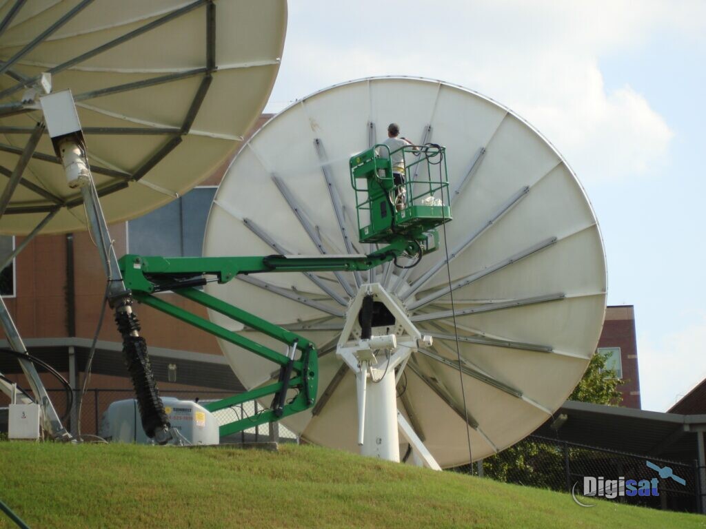 Technician servicing a satellite antenna from a boom lift