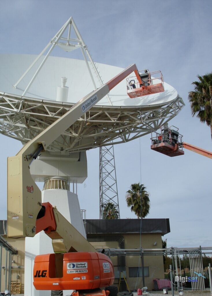 Crews in lift buckets servicing a large earth station antenna