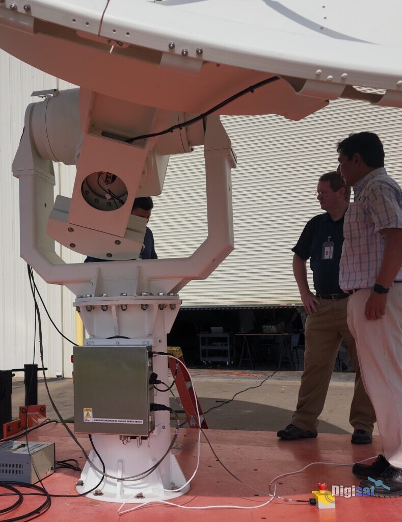Engineers inspecting an antenna positioner during factory testing