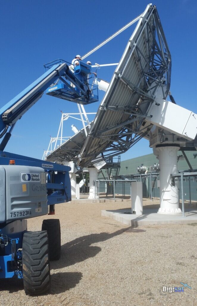 Crew servicing a large teleport antenna from a boom lift